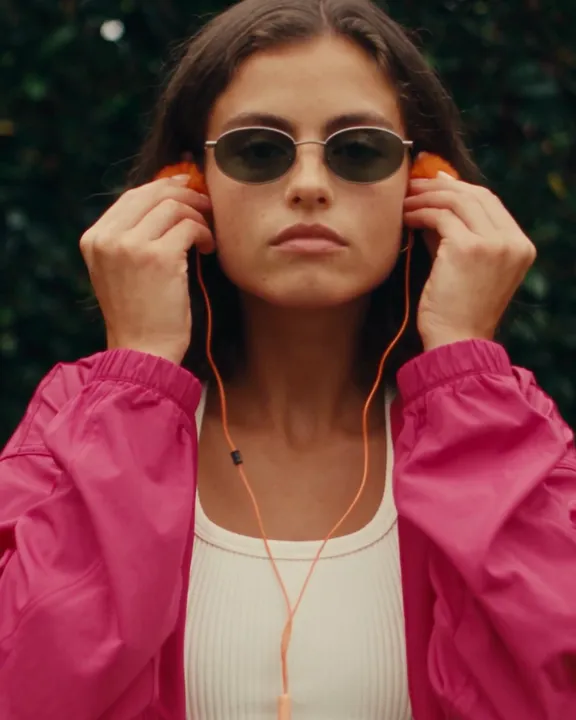 Sunglasses, wired earphones and a pink windbreaker